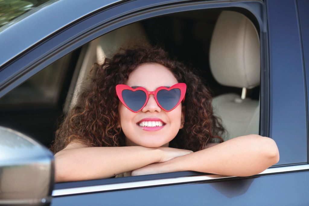 Young woman wearing heart shaped glasses in car