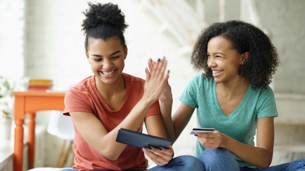 Cheerful teenage girls shopping online with a credit card