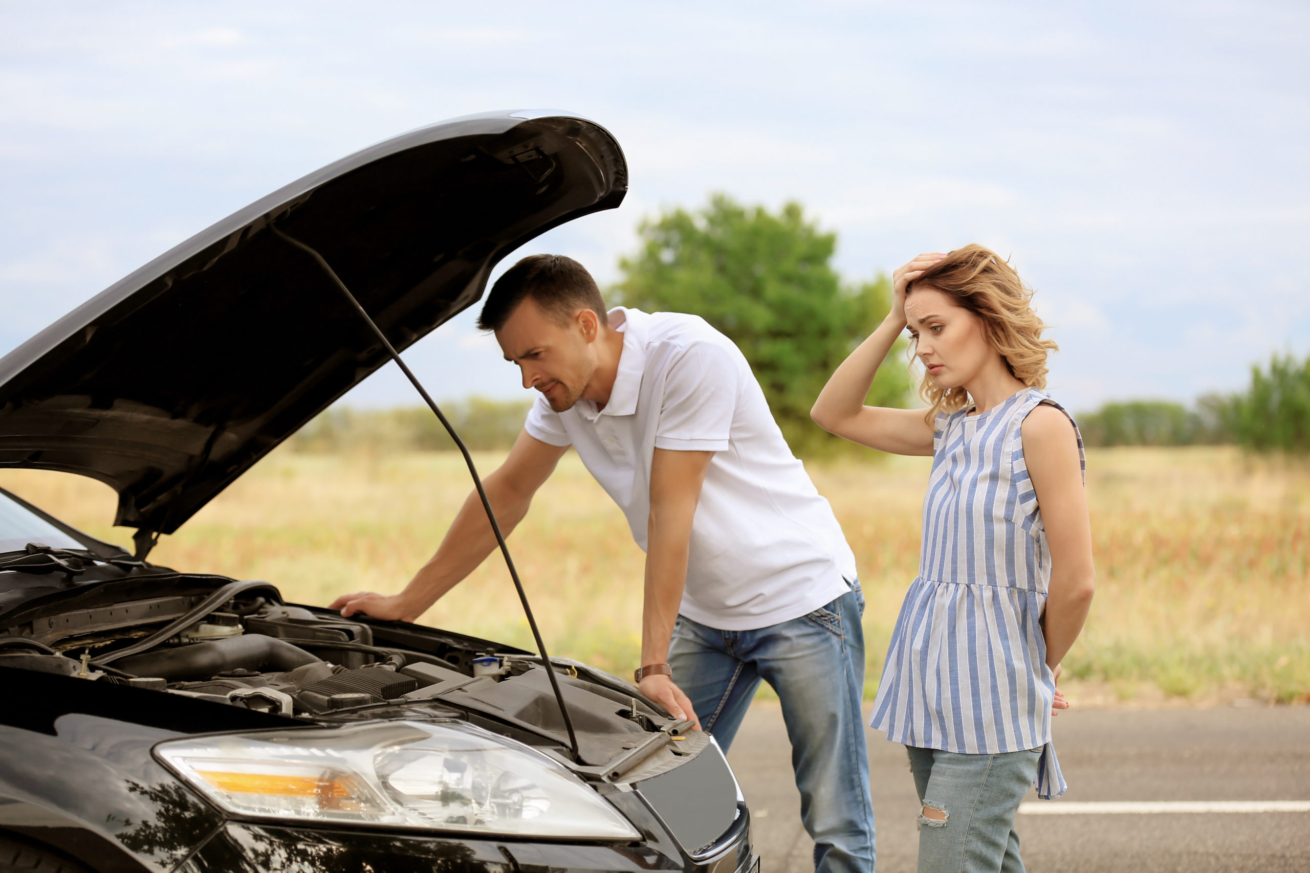 Young couple standing near broken car Young couple standing near broken care