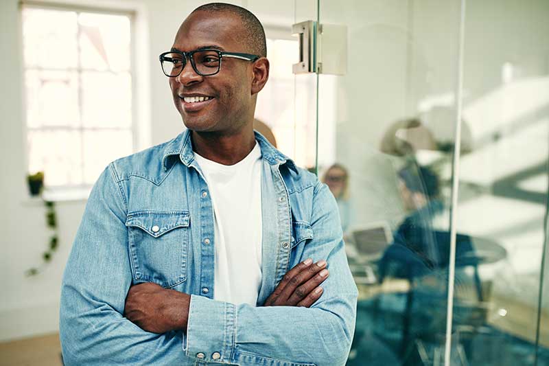 Image of a smiling young African businessman standing in a modern office