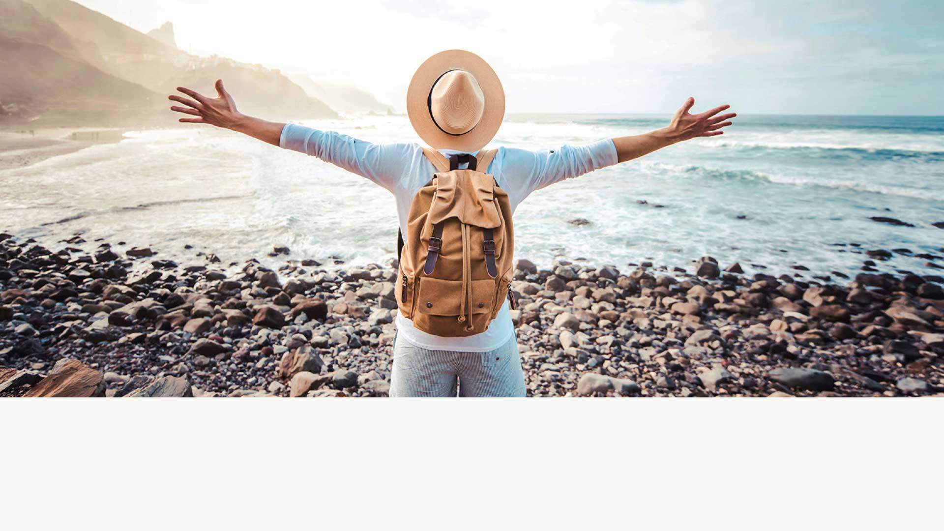 Happy tourist with backpack enjoying freedom raising arms up