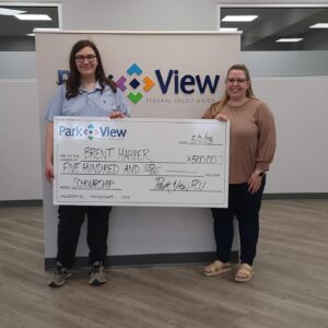 Brent Harper, 2023 Scholarship Winner, holds a giant, oversized check with Broadway Park View FCU Branch Manager Jordan Tyler.