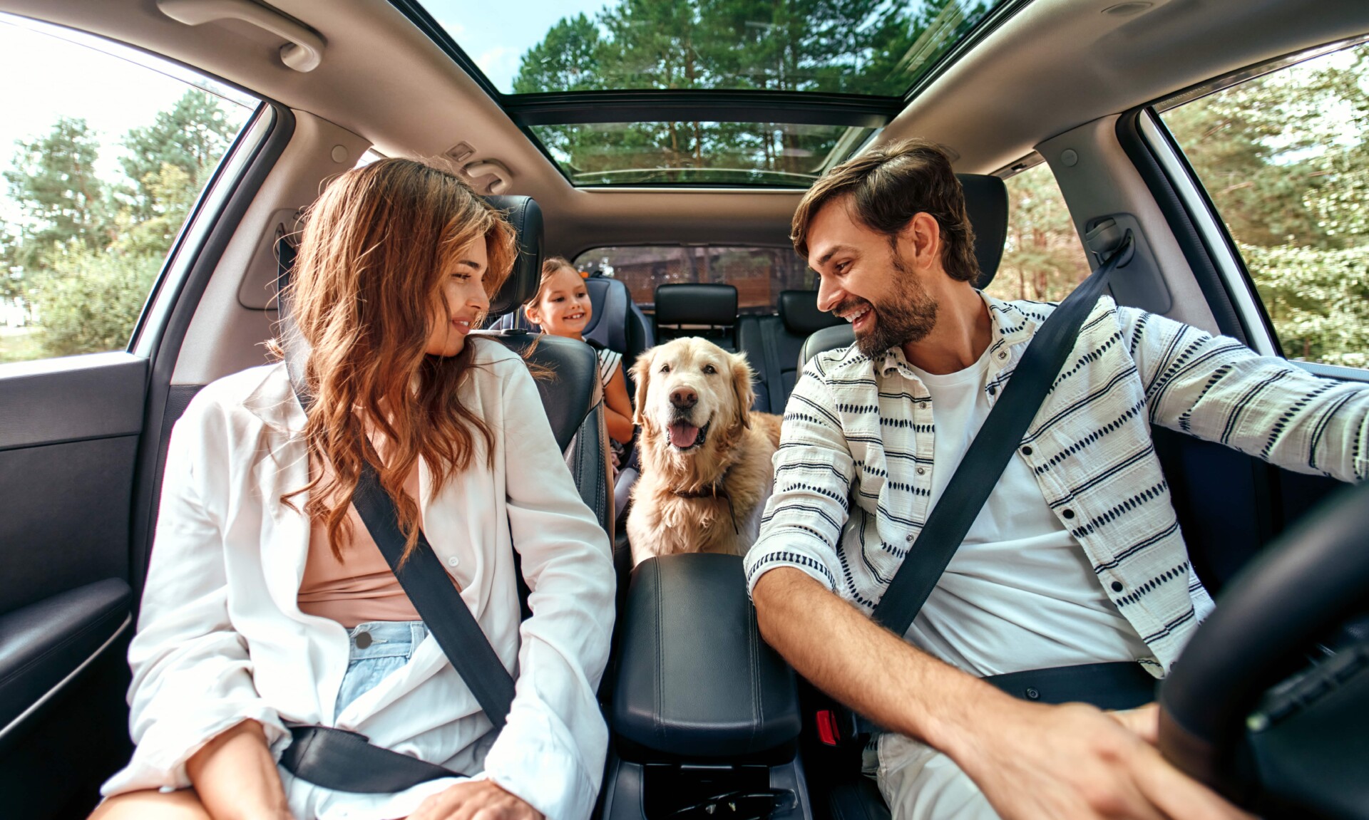 Family in car -Auto Loan A family of four, including a dog, happily seated in their new car, financed through an auto loan.