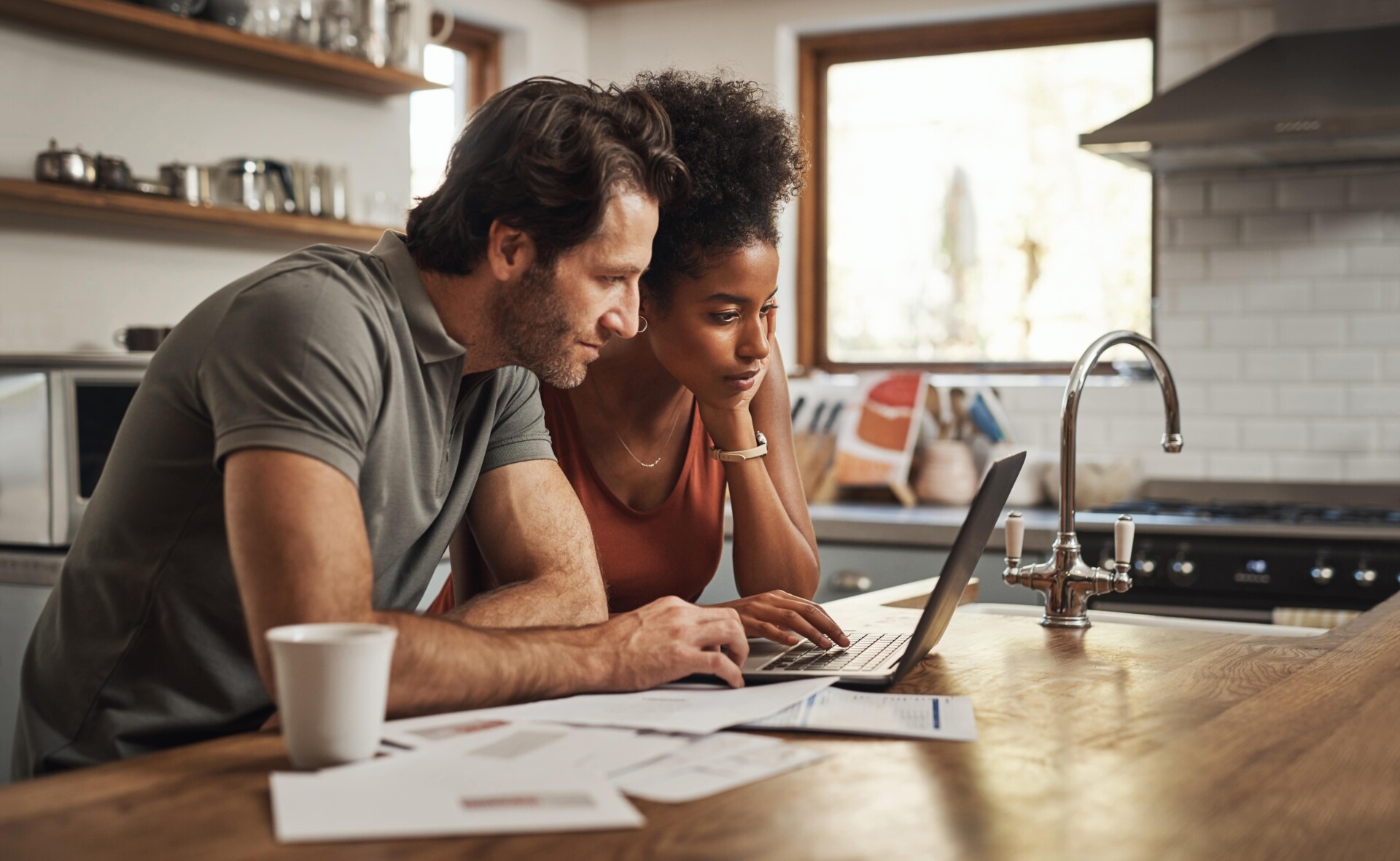A man and woman working on a laptop in a kitchen, likely discussing or applying for an express loan.