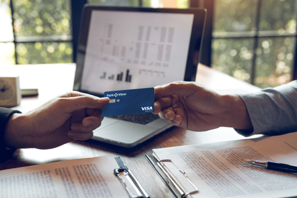 A business person handing another business person a Park View Business Visa Credit Card