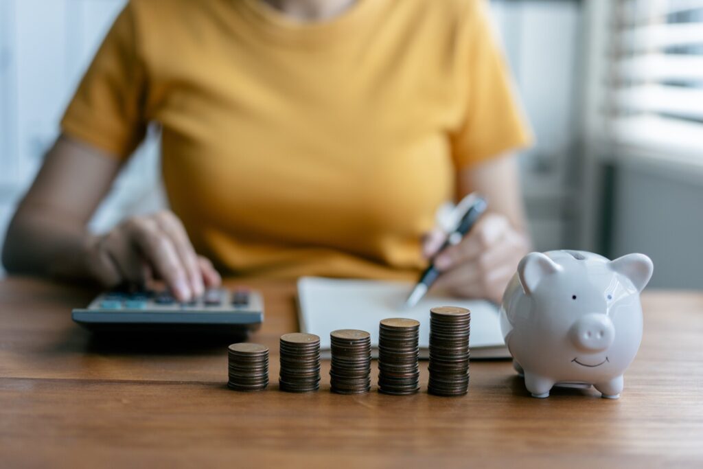 Woman calculating savings with coins, celebrating National Financial Awareness Day by managing her finances wisely.