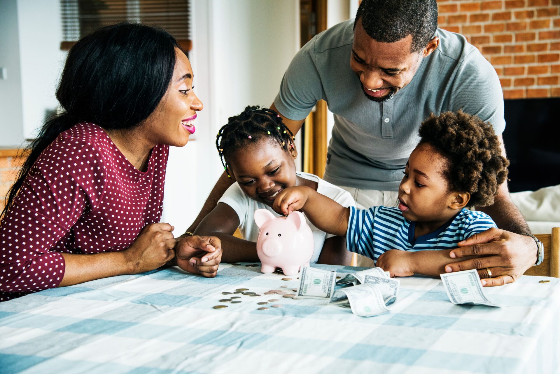 A family teaches kids to save by putting coins into a colorful piggy bank together, smiling and enjoying the moment.