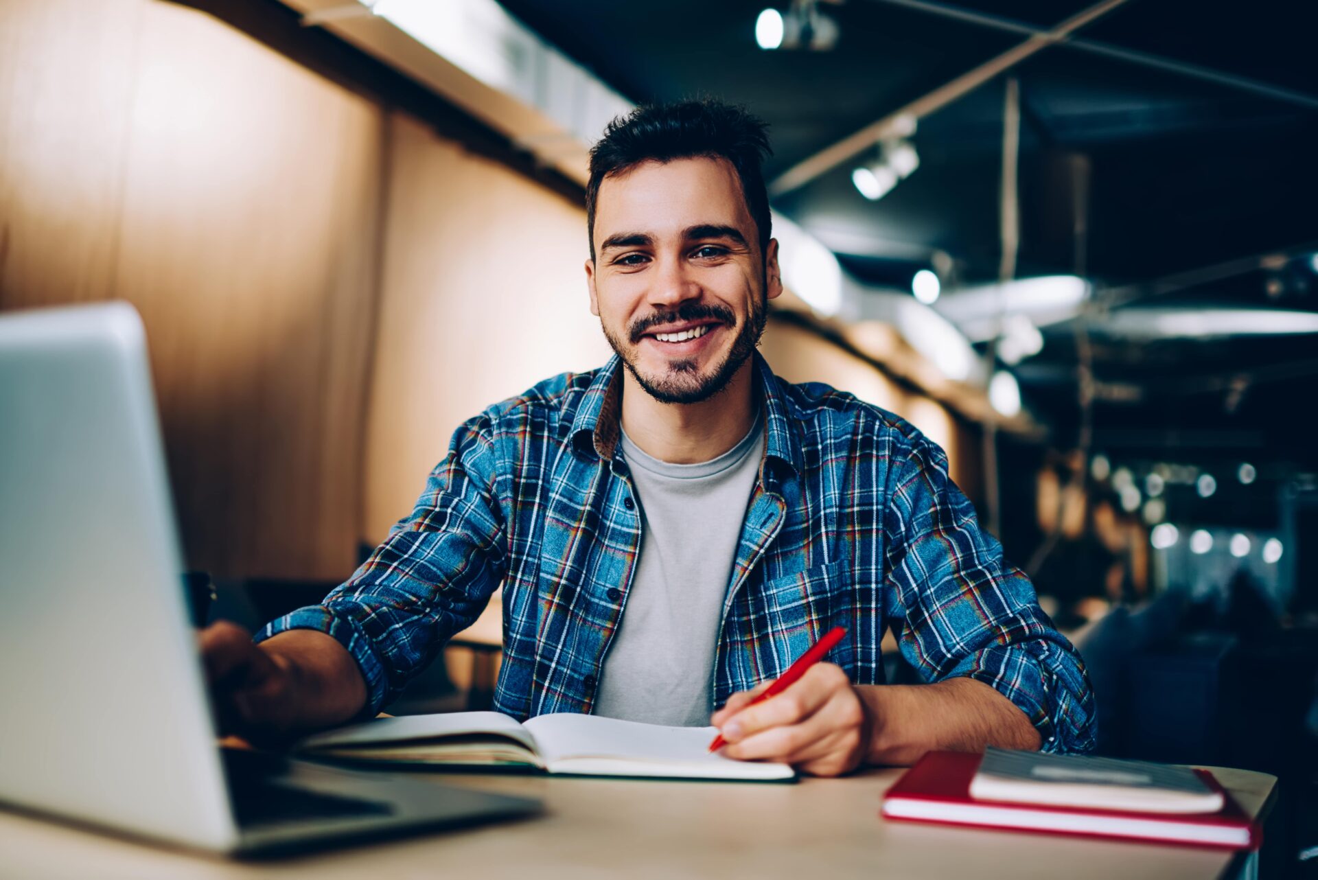 A college student sits at a table with a laptop, symbolizing academic life and student loans.