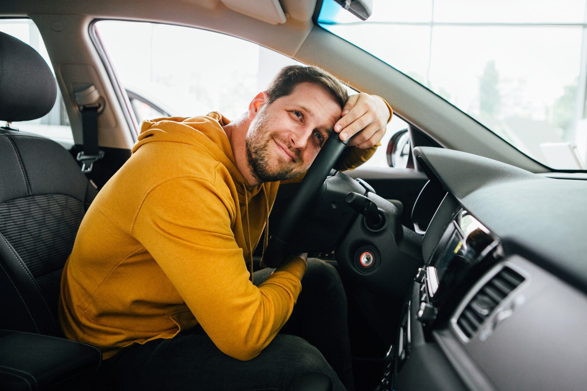 Man in the driver's seat of a car appears to be thinking about an auto loan.
