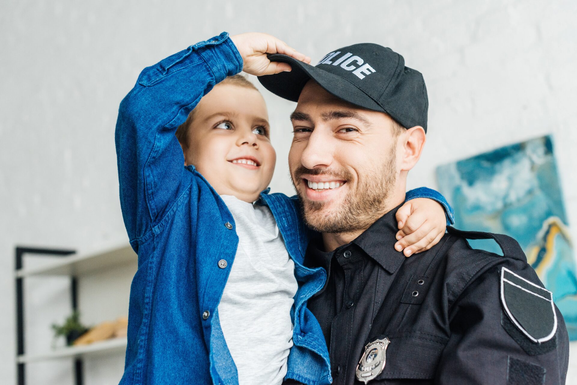 A police officer in uniform holds a child, representing community partnership in a homeownership program.