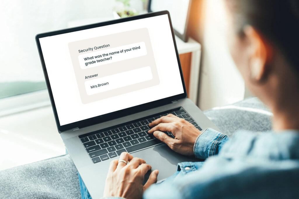 A person using a laptop enters "Mrs. Brown" as the answer to a security question asking for the name of their third grade teacher.
