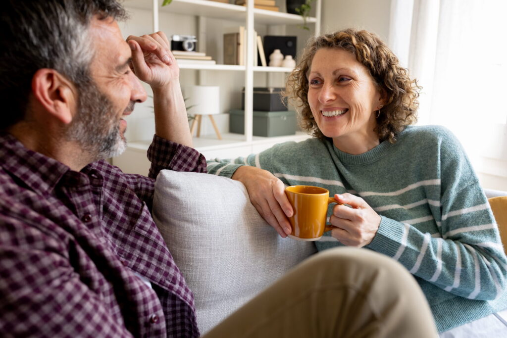 Happy mature couple relaxing on sofa talking and smiling