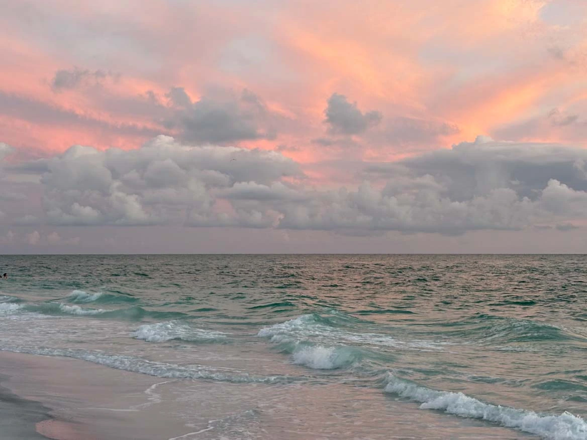 A serene beach at sunset, with gentle waves lapping the shore and colorful clouds in the sky.