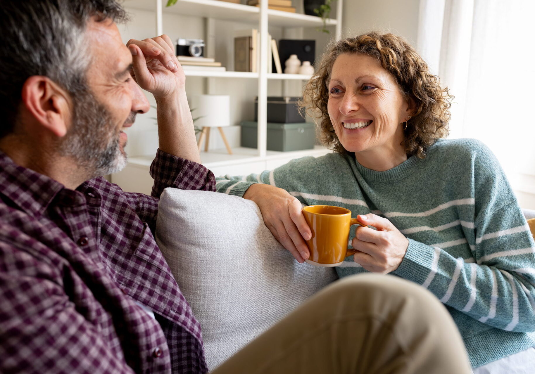Happy mature couple relaxing on sofa talking and smiling