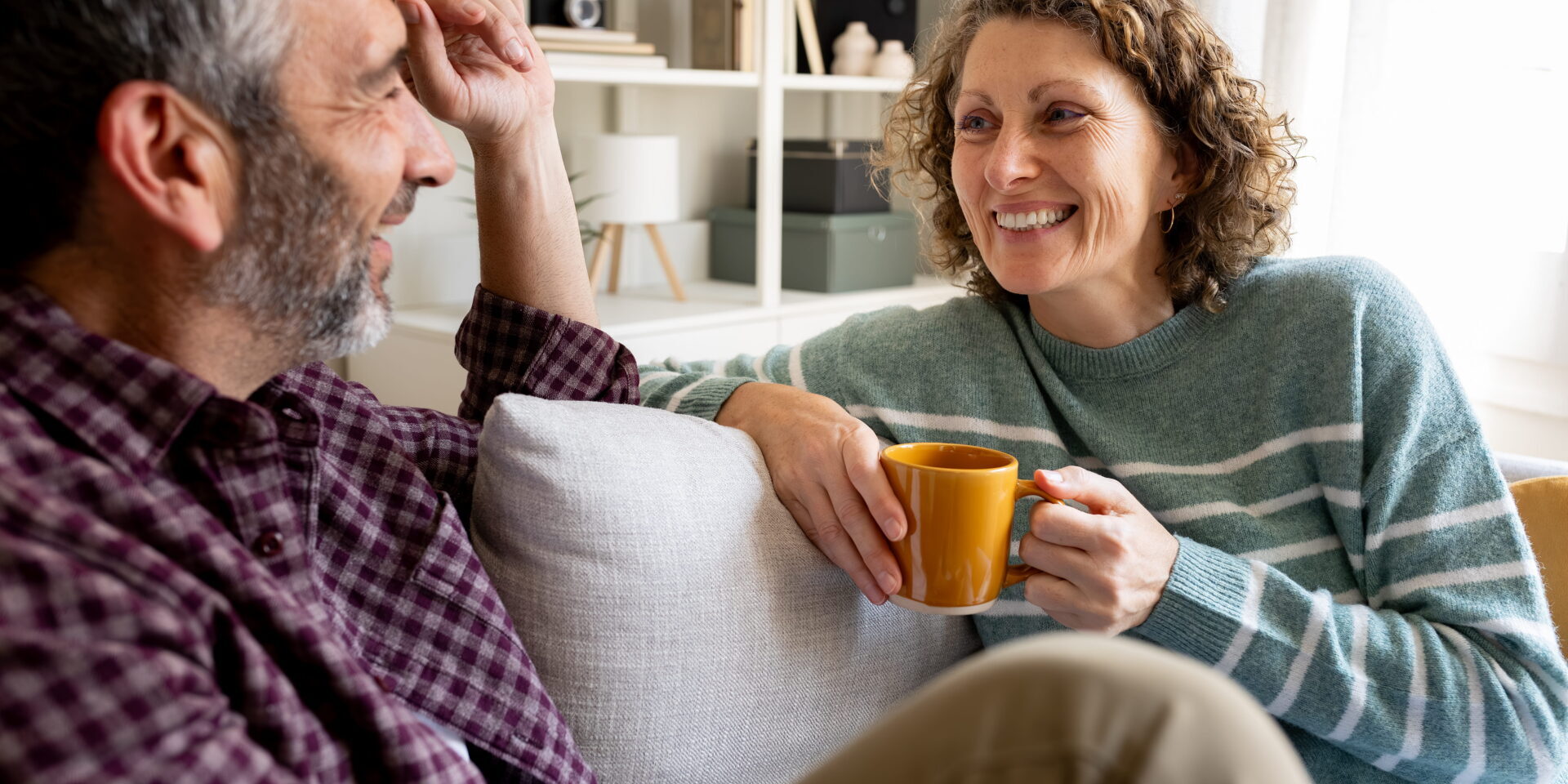 Happy mature couple relaxing on sofa talking and smiling