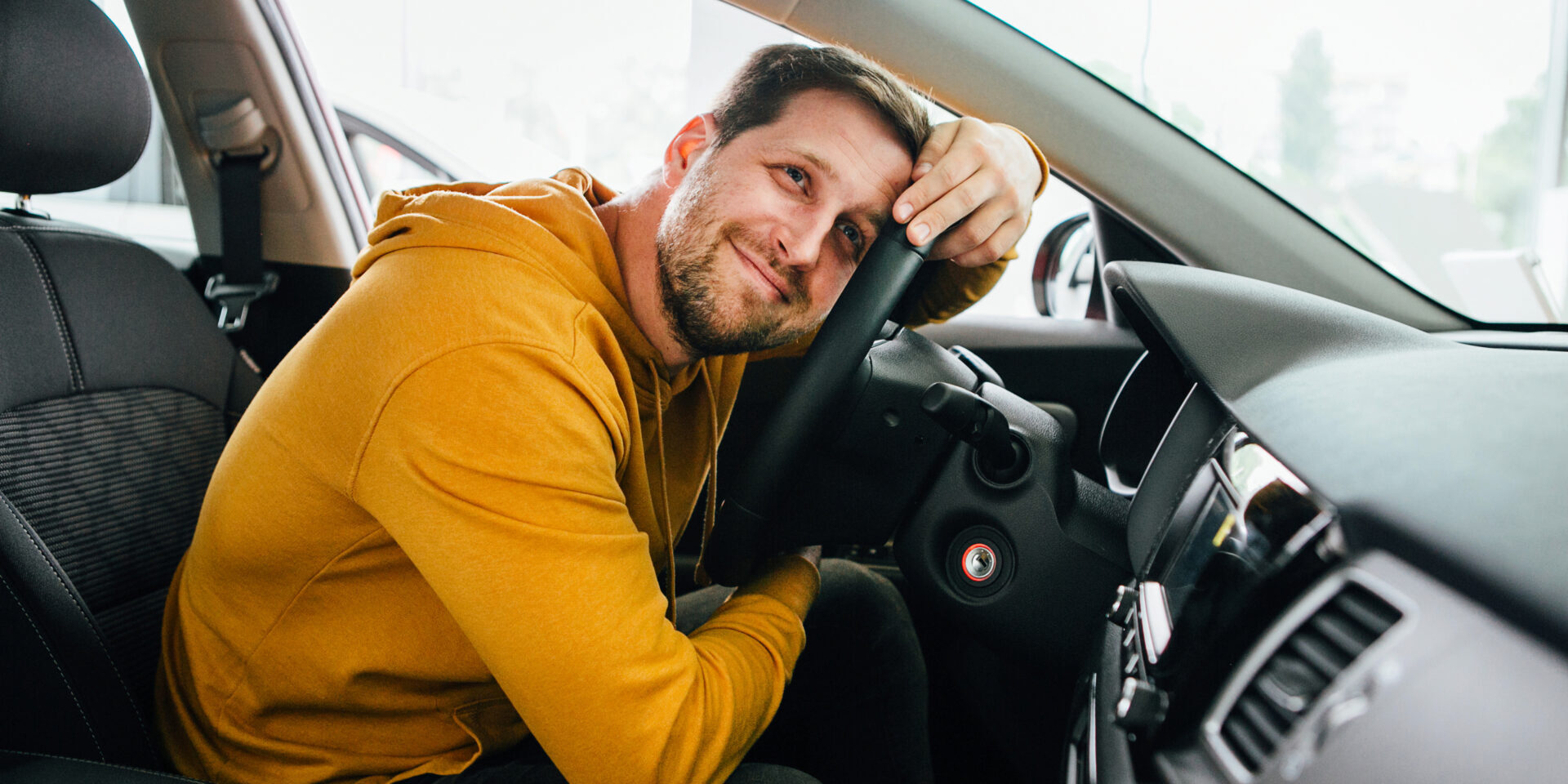 man in the driver's seat of a car appears to be thinking about an auto loan.