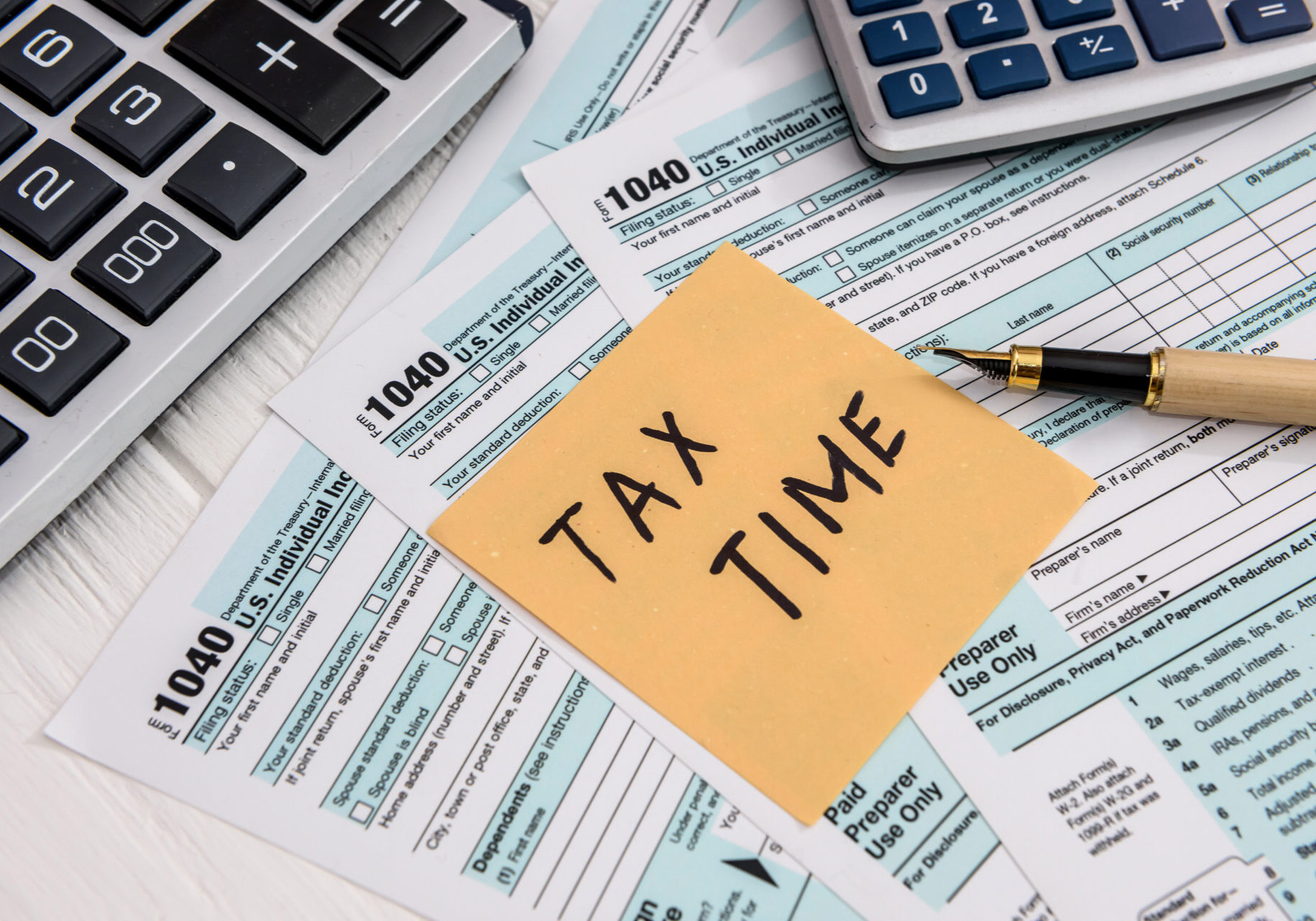 Tax forms and a sticky note that states "tax time" on a table.