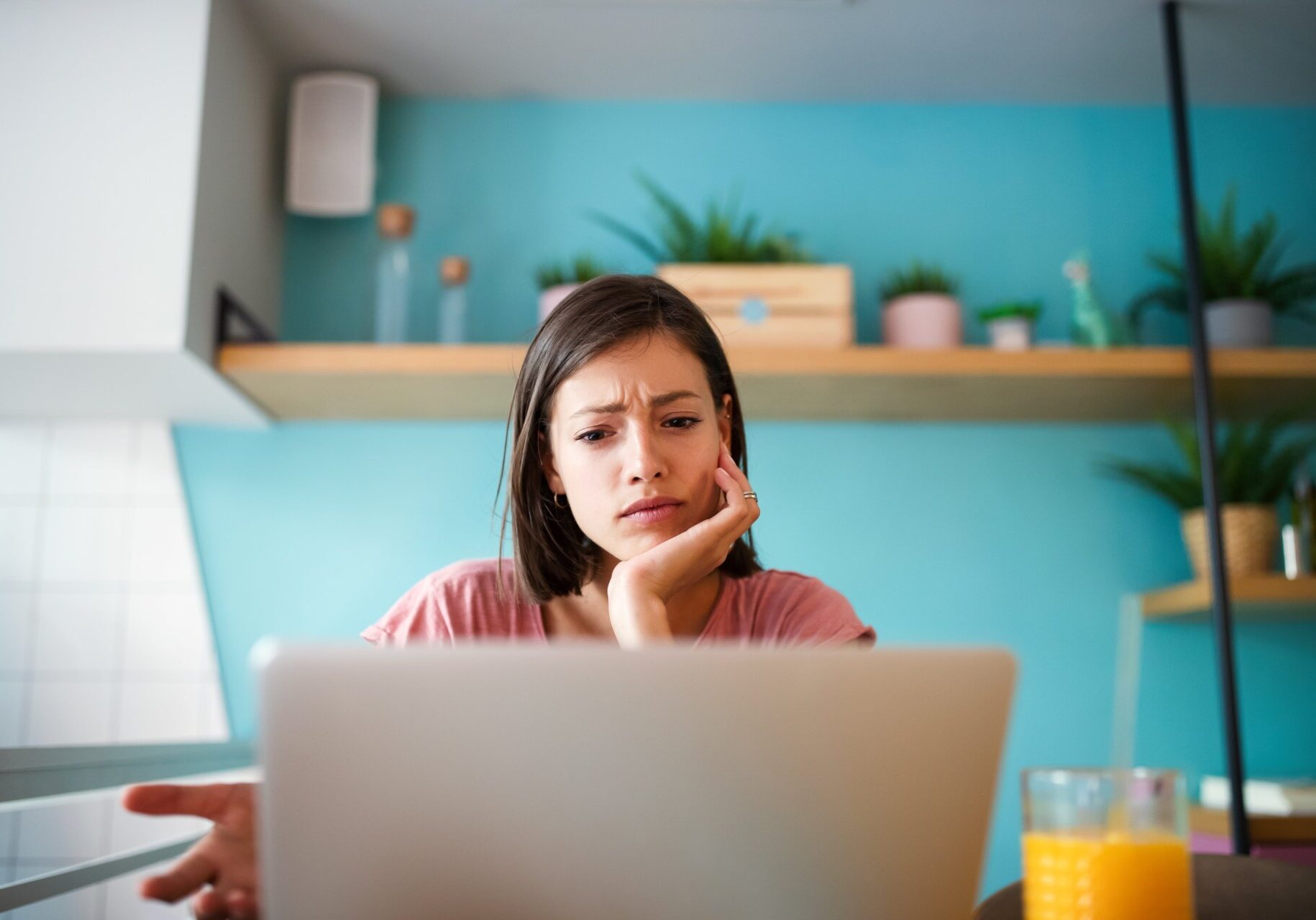 A woman sits at a table with a laptop, looking concerned about a potential data breach.