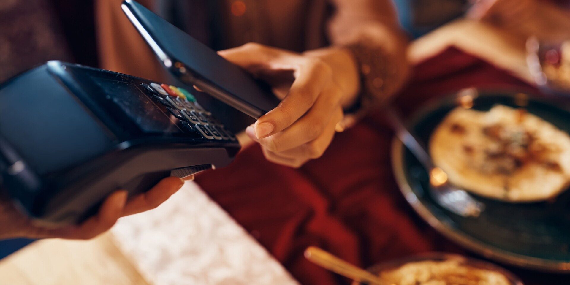 A woman is using her digital wallet to settle the bill for her meal at a restaurant, highlighting a dining transaction.