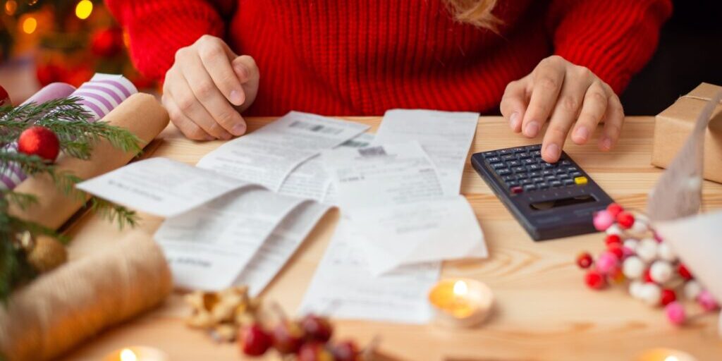 Woman calculating her Christmas budget with a calculator, focusing on effective holiday budgeting tips.