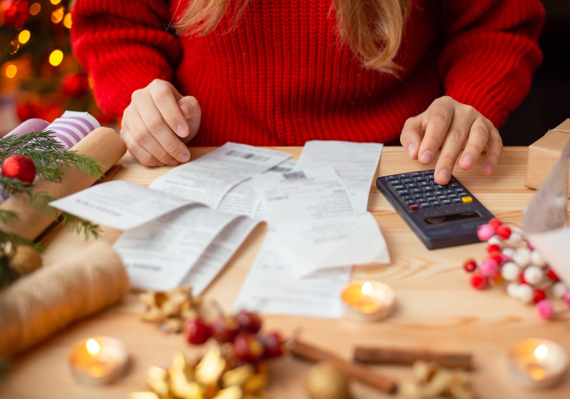Woman calculating her Christmas budget with a calculator, focusing on effective holiday budgeting tips.