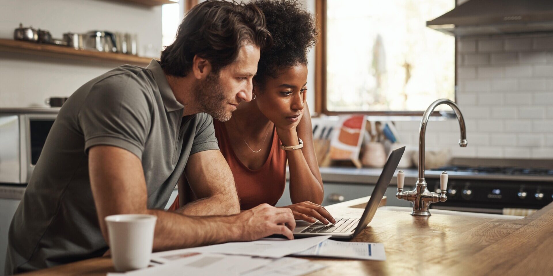 A man and woman working on a laptop in a kitchen, likely discussing or applying for an express loan.