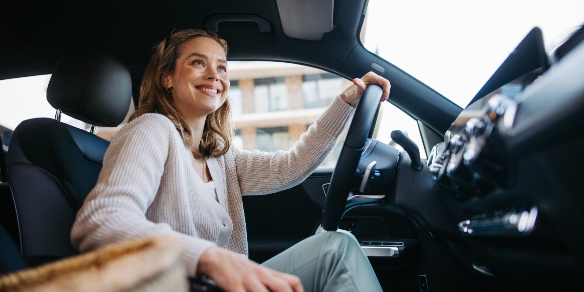 A woman sits in the driver's seat of a car, looking confident as she explores options for an auto loan.