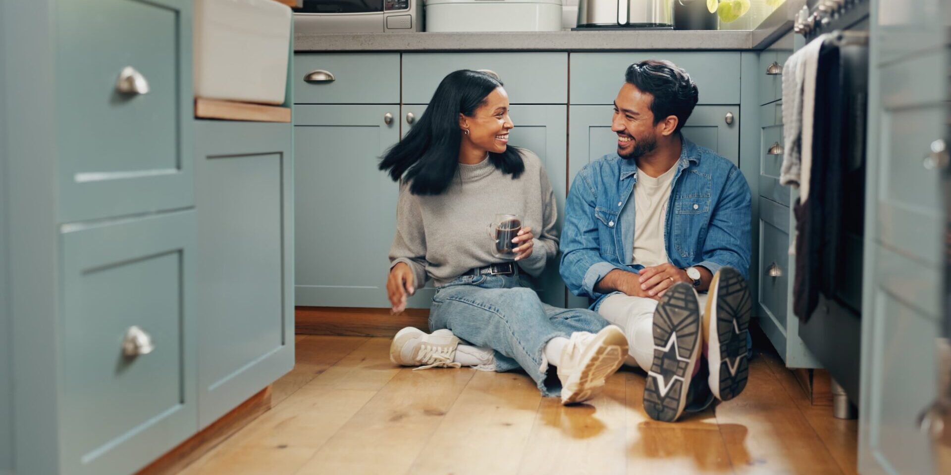 A couple sitting on the kitchen floor, surrounded by homey decor and a warm atmosphere.