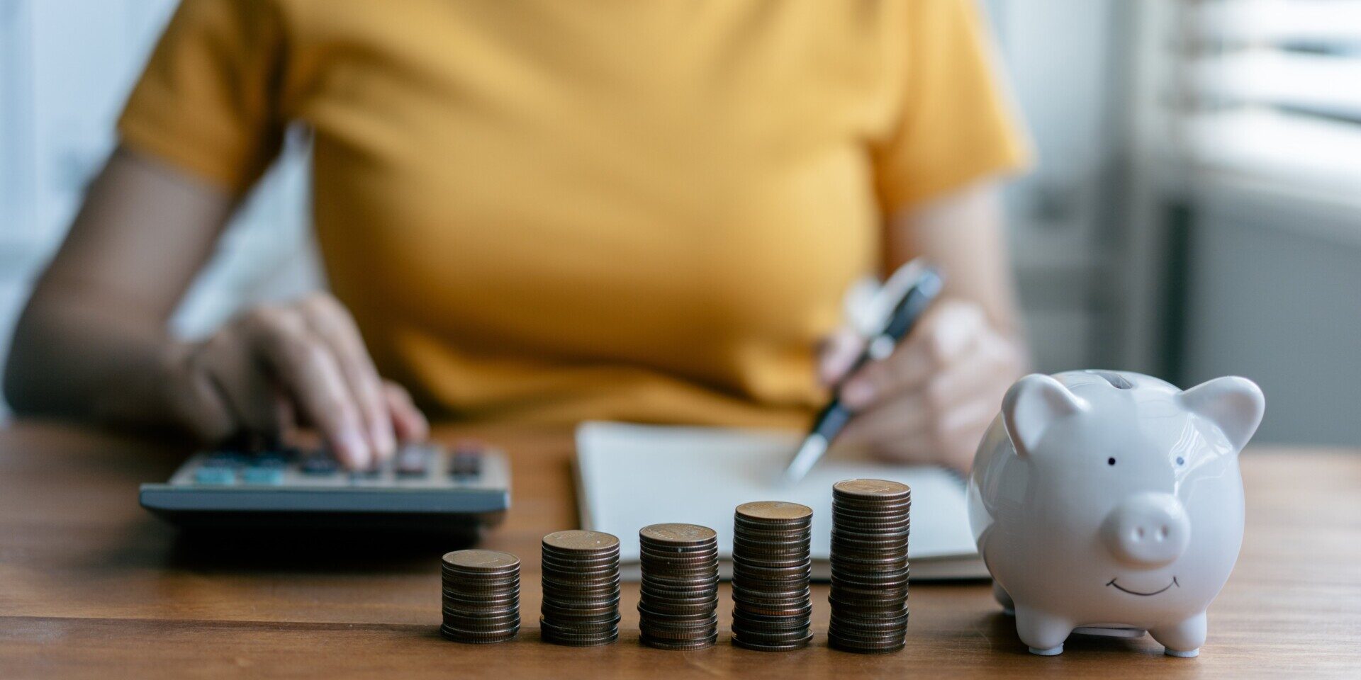 Woman calculating savings with coins, celebrating National Financial Awareness Day by managing her finances wisely.