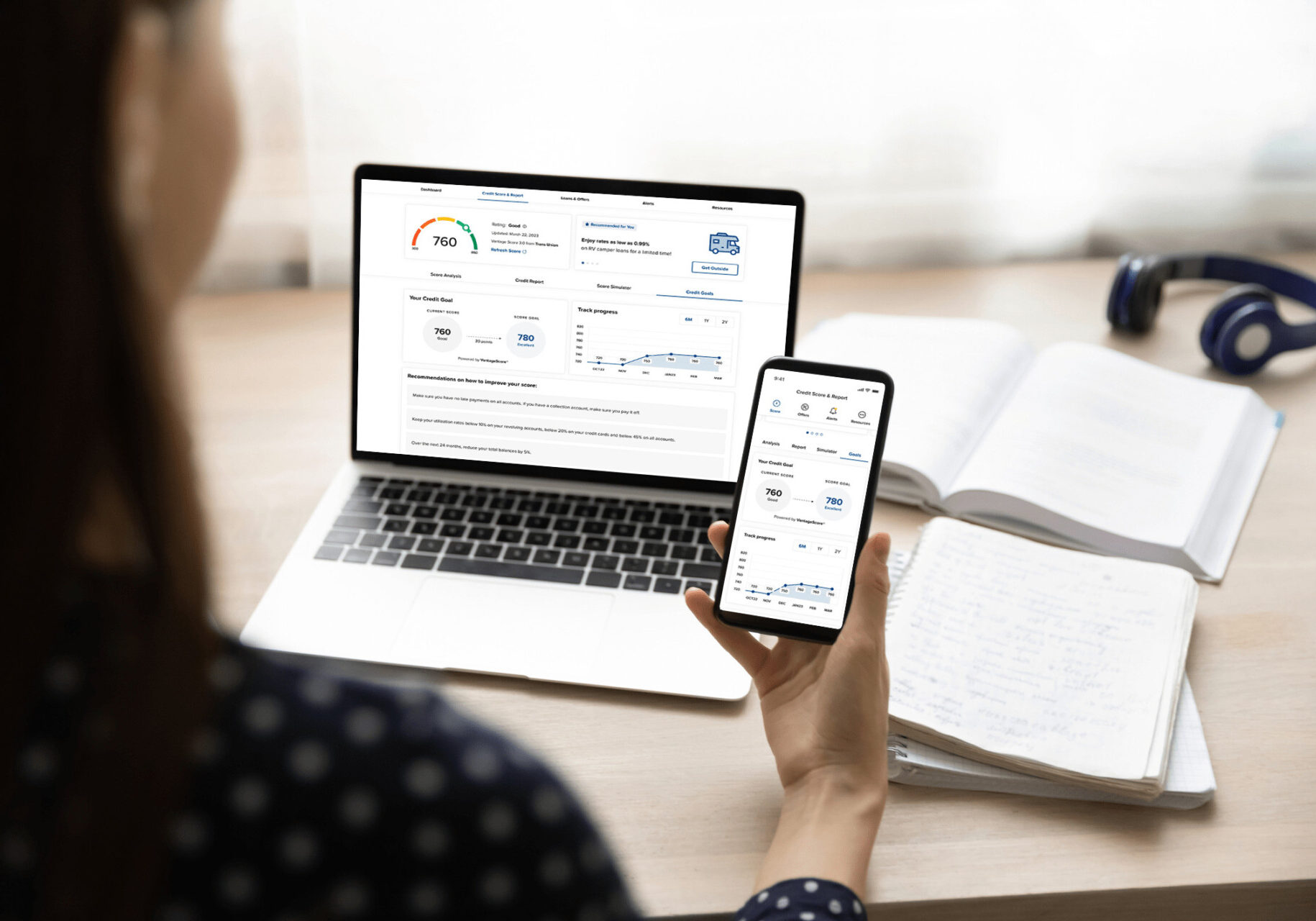An individual engaging with a mobile app and computer designed to track and monitor, while helping them understand credit scores effectively.