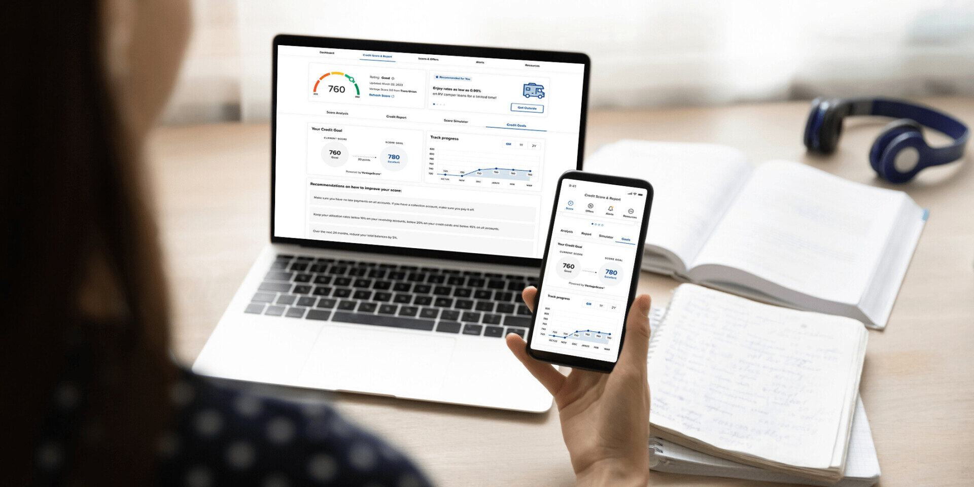 An individual engaging with a mobile app and computer designed to track and monitor, while helping them understand credit scores effectively.
