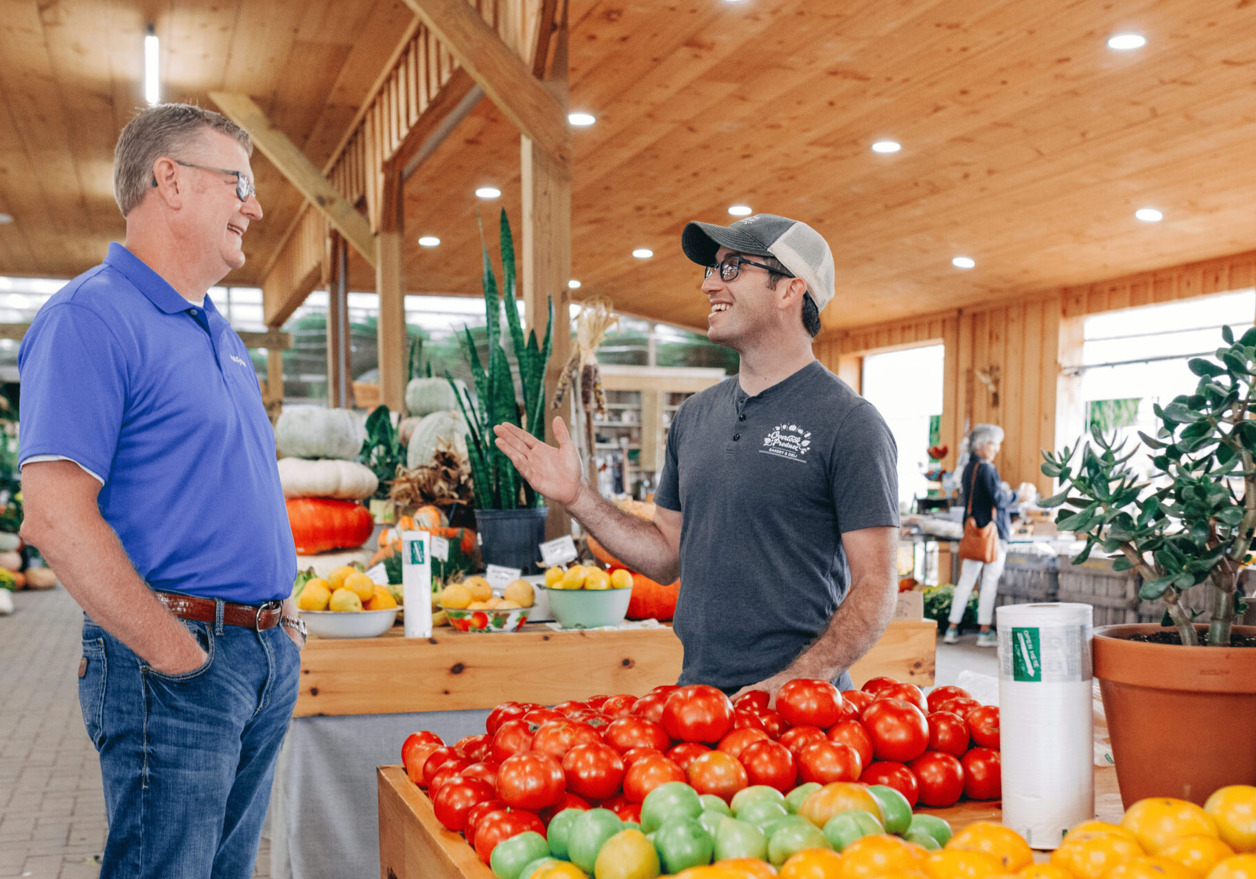 Park View Business Loan officer stands to the left of a Park View Business member in a brightly colored produce store.