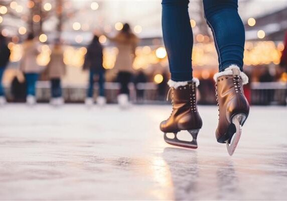 A person glides on ice, illuminated by colorful lights in the background, creating a festive atmosphere.
