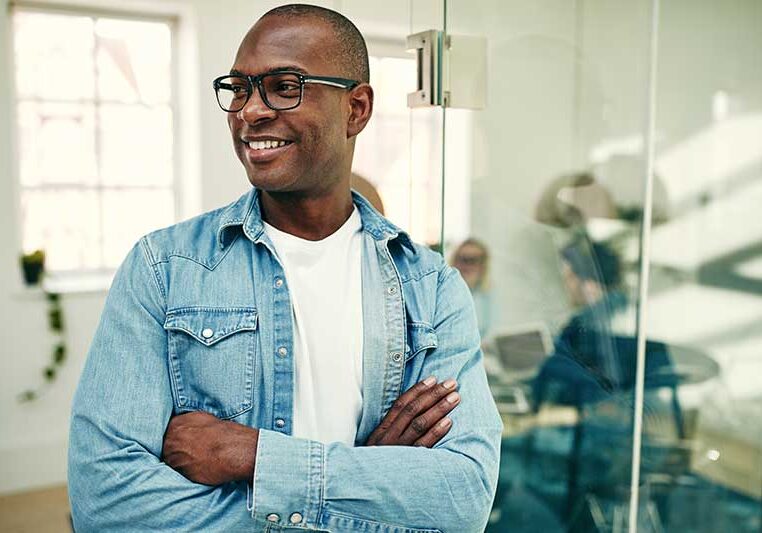 Image of a smiling young African businessman standing in a modern office