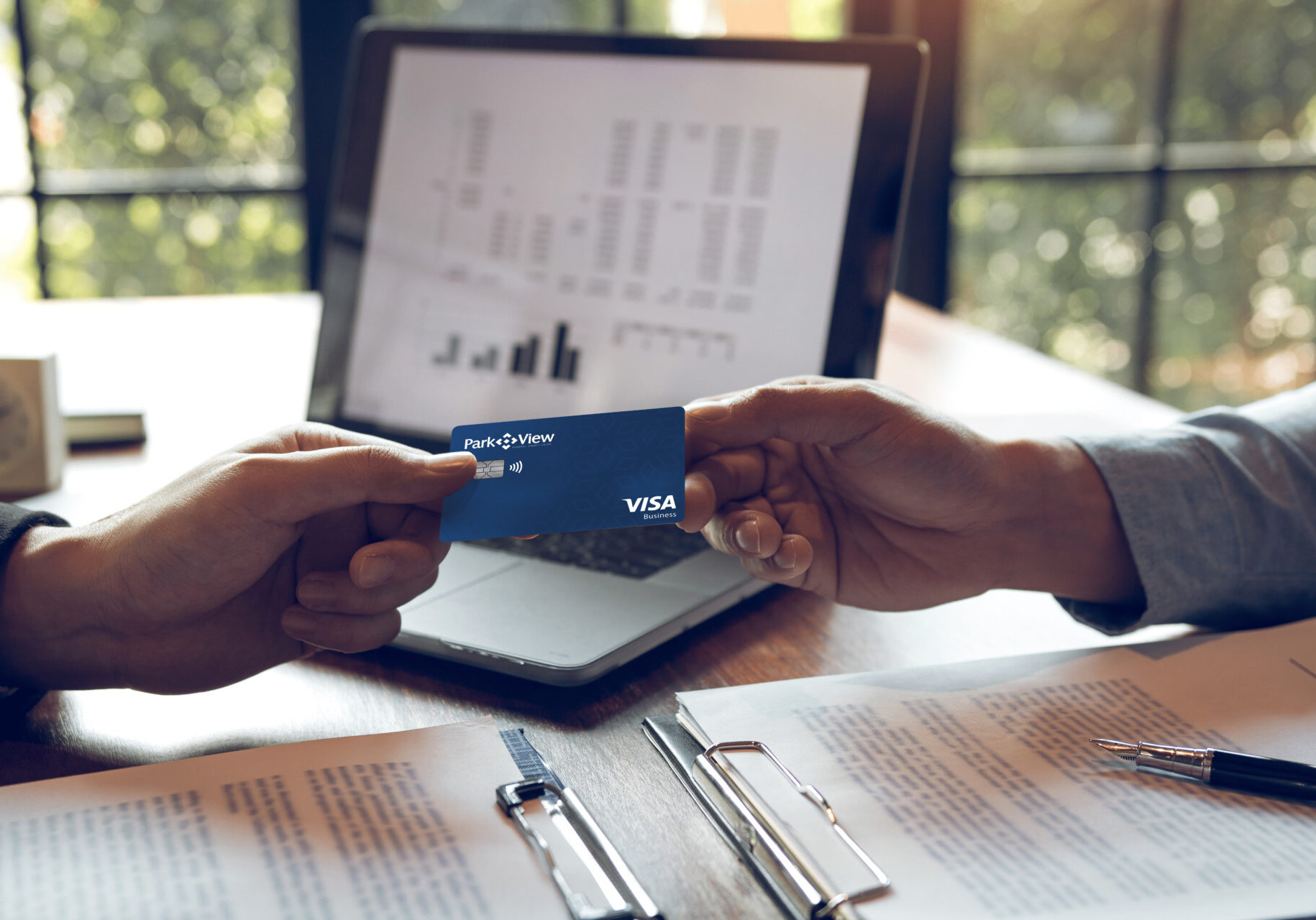 A business person handing another business person a Park View Business Visa Credit Card