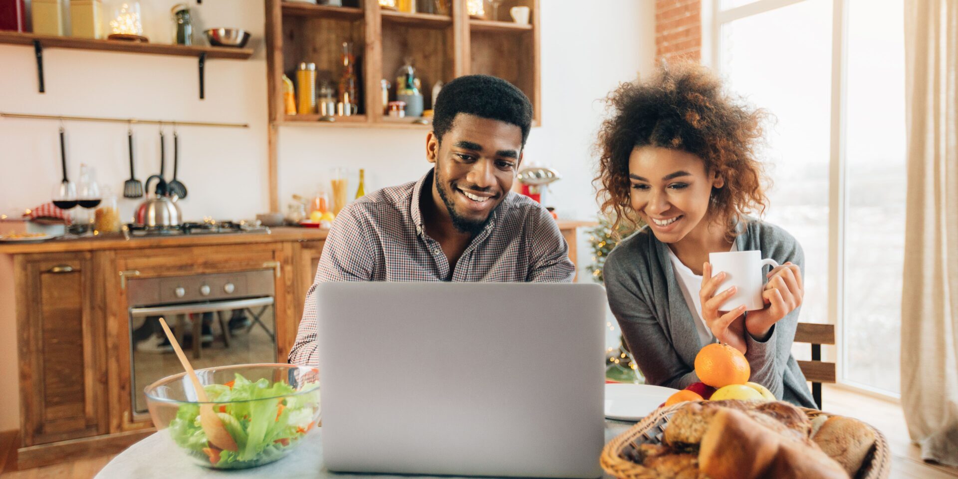 Happy african-american couple using laptop at kitchen