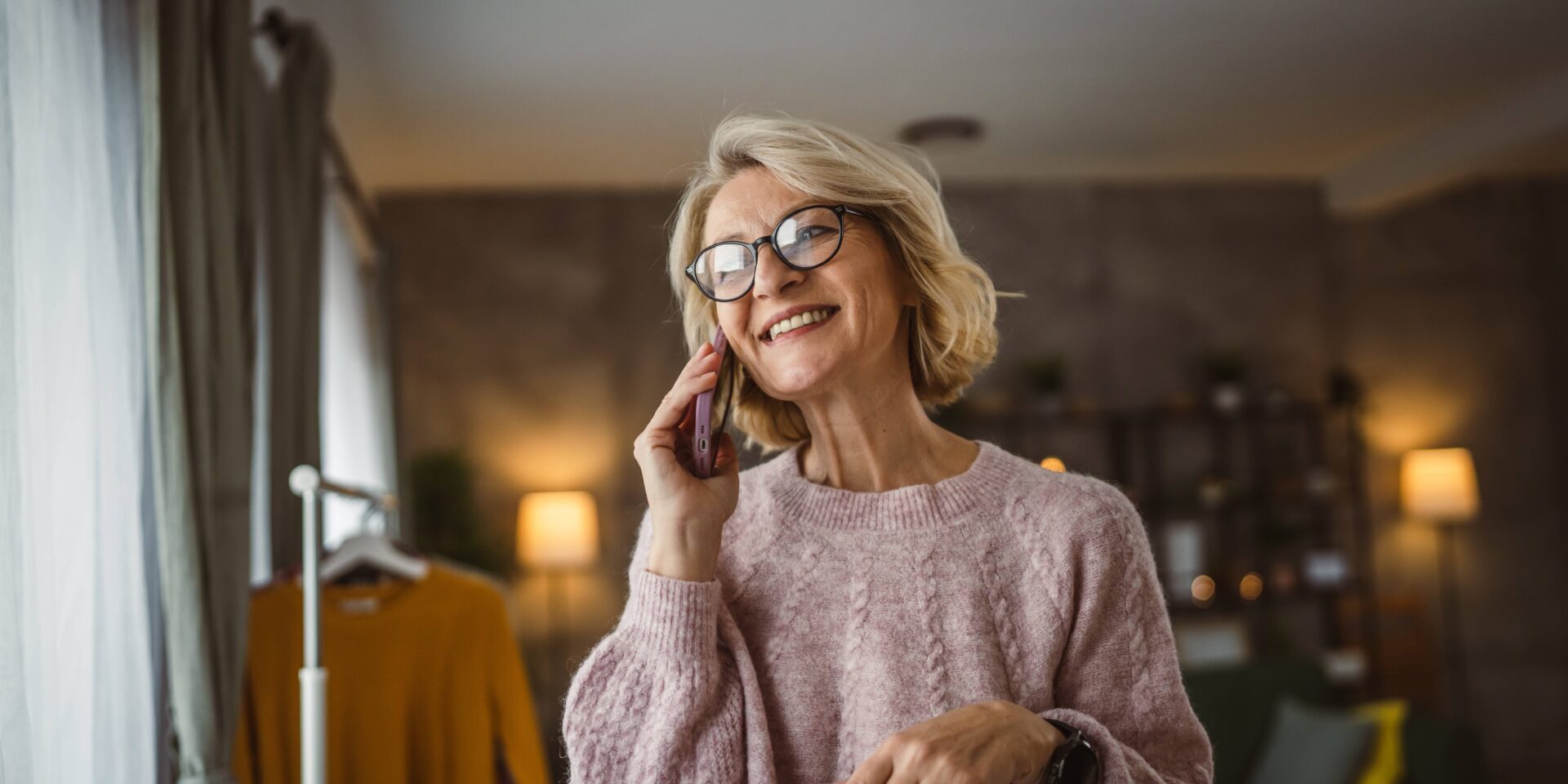 older woman smiles while holding a cellular phone to her ear